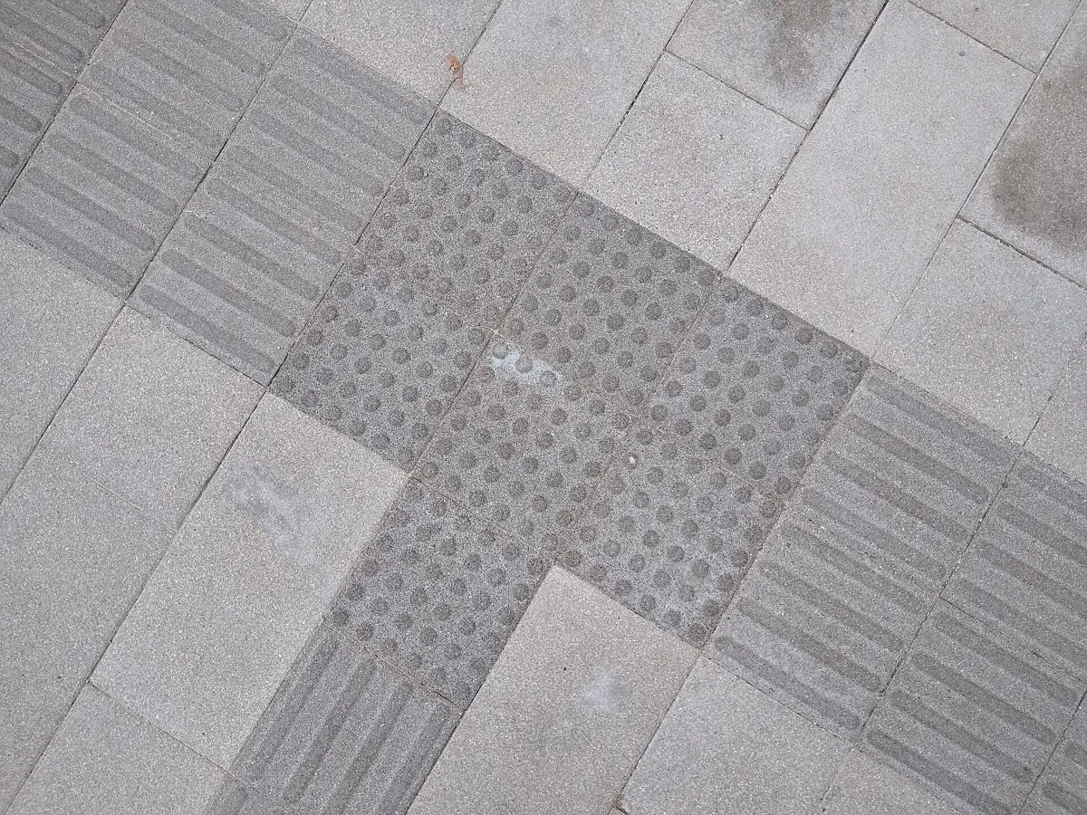 Grey tactile paving with domes and bars on a pavement in China